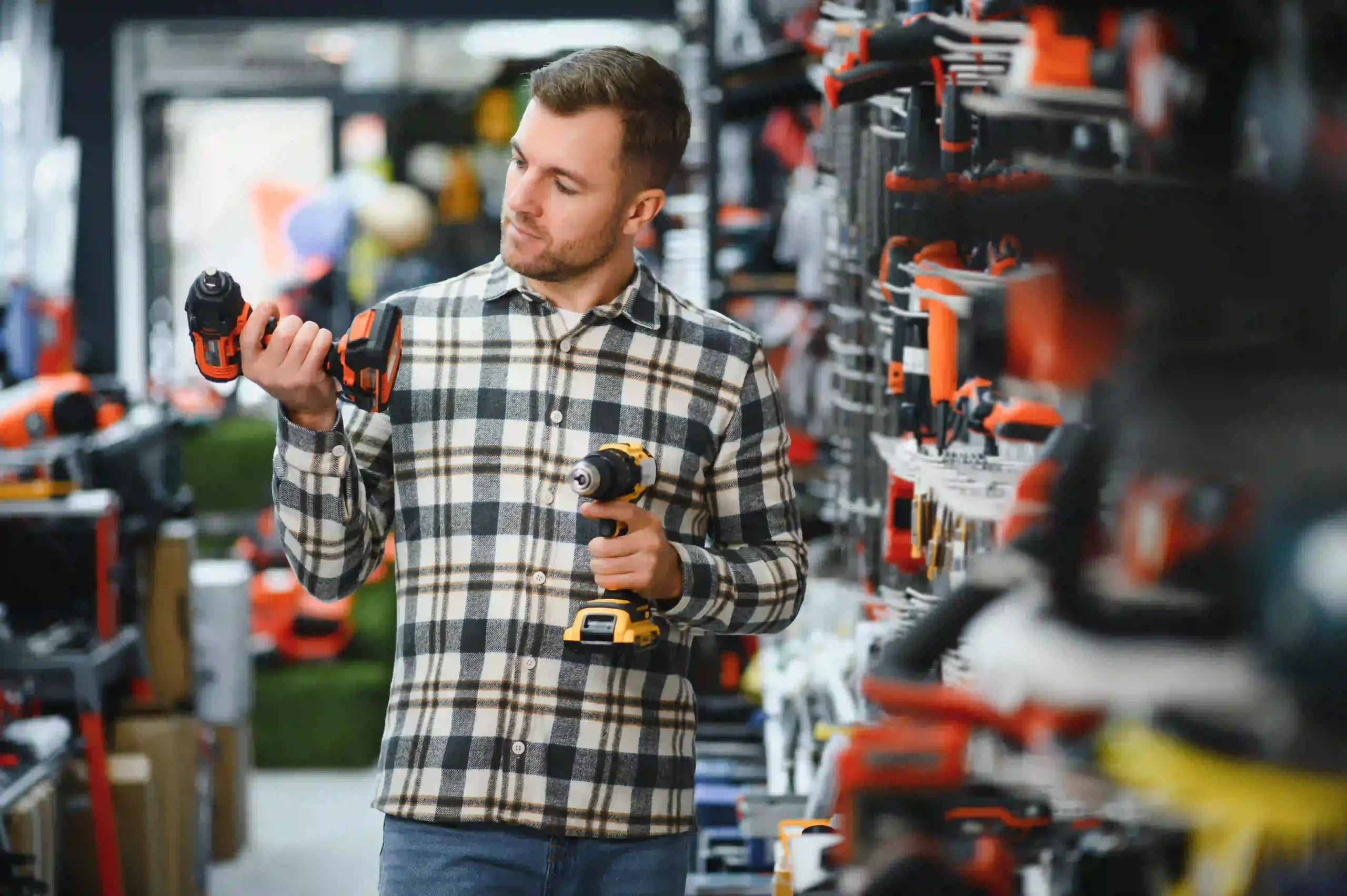 Mann vergleicht Akkubohrer im Baumarkt.