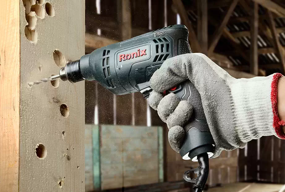 A man using a Ronix drill driver to make holes in a piece of wood