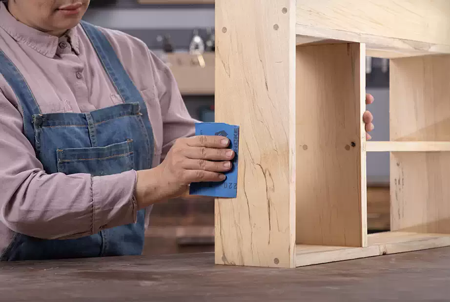 Sanding the DIY wooden shelf with a sandpaper