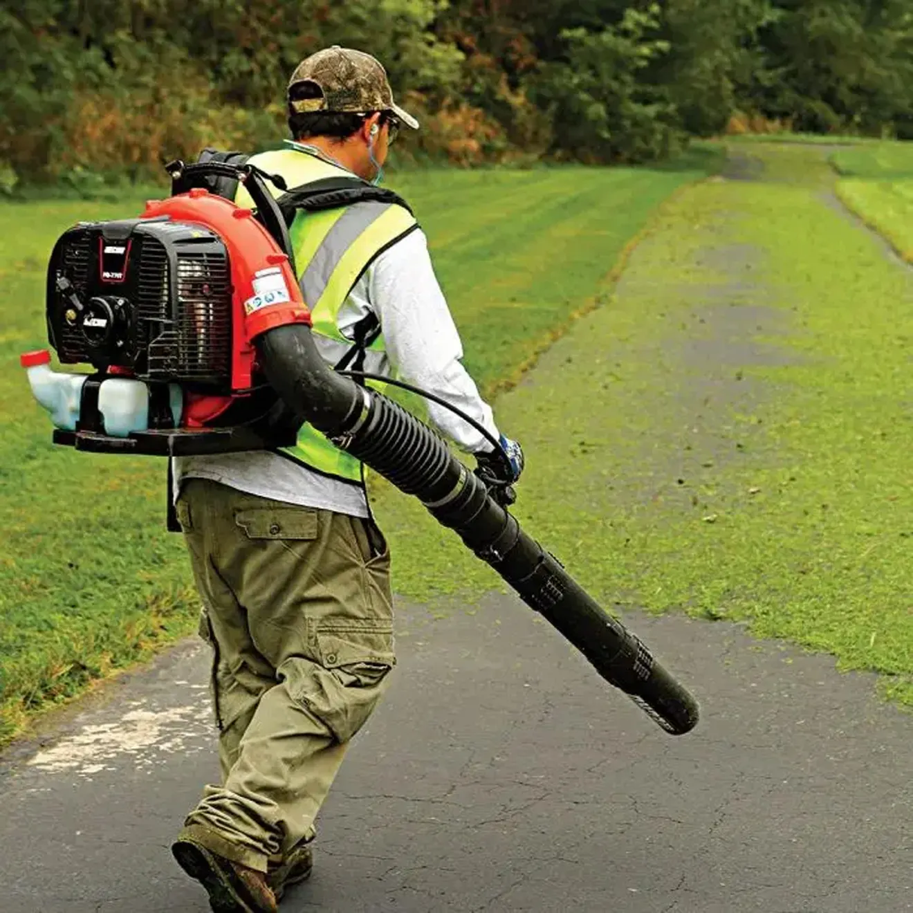 back view of a man holding a gas-powered leaf blower