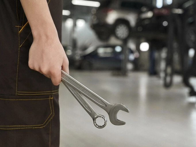 a person holding wrenches in hand in a repair shop