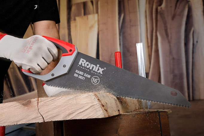 A handsaw is being used to cut wood