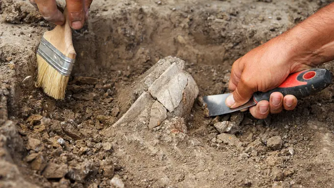Using digging hand tools for excavation on an archeological site