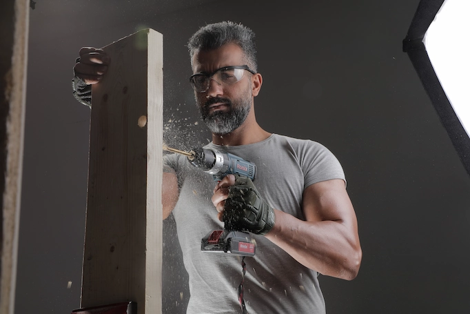 A drill/driver is being used to cut holes into wood