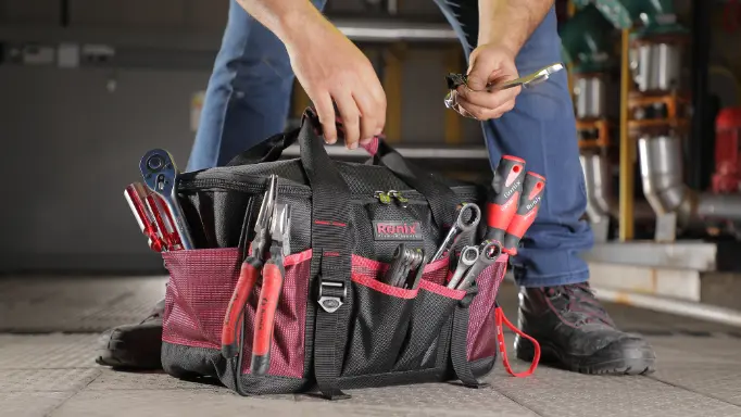 A man drawing a wrench out of his well-stocked Ronix tool bag