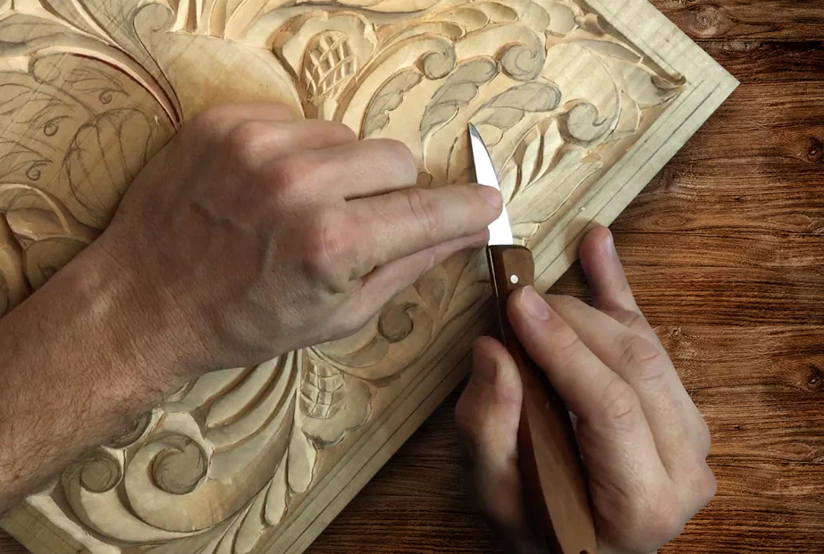 Using a carving knife to cut out an intricate pattern on wood