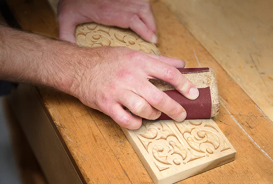 Using a sandpaper on a carved workpiece