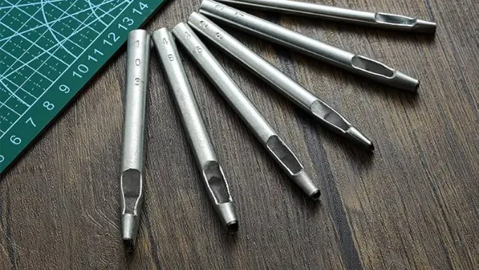 A series of metal hole punches besides a cutting mat