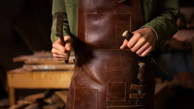 A man holding leatherworking tools in hand
