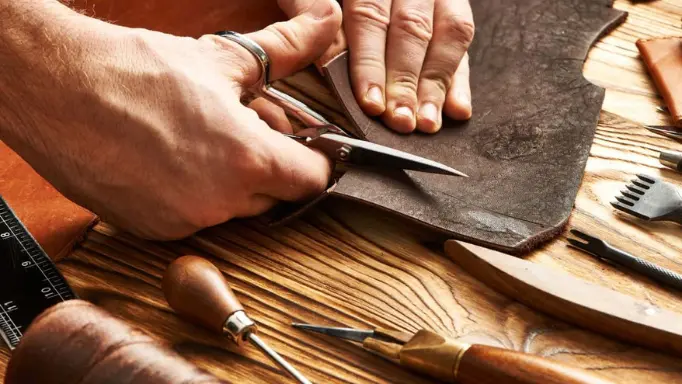 A man cutting leather using scissors  