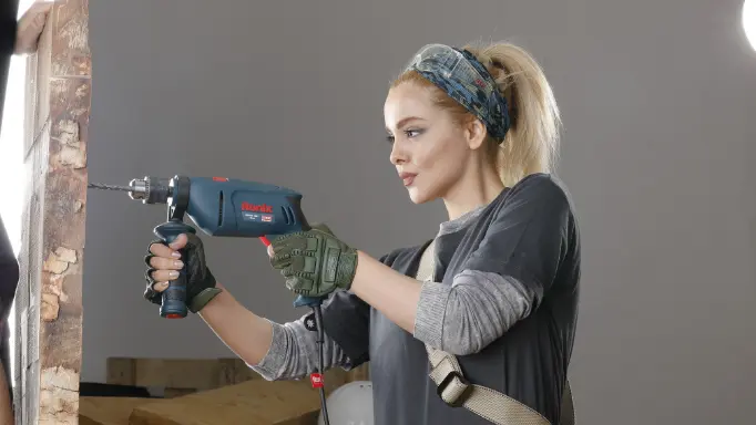 A DIYer using a Ronix corded hammer drill on the wall