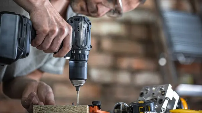 A man using a cordless screwdriver to drive screws into wood