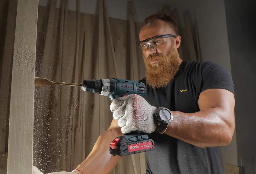 a man using a Ronix drill to make a hole in the wall