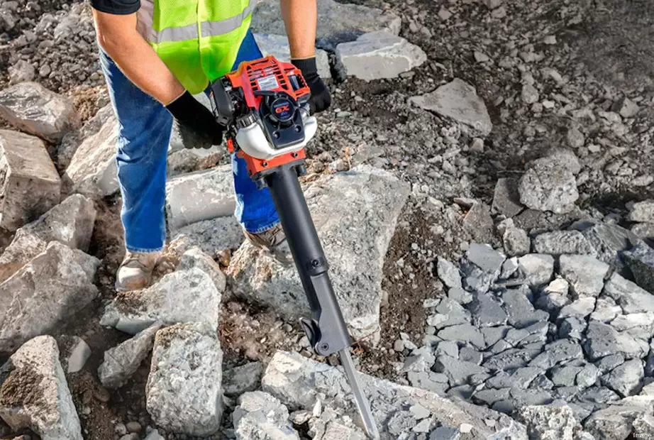 A man is cracking stones using demolition hammer