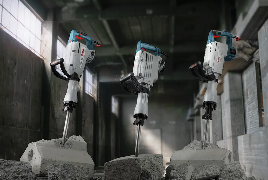 Three jack hammers being placed upside down on concrete blocks