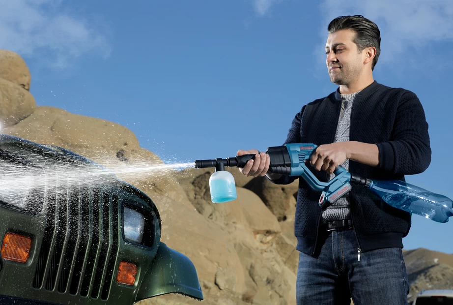 A man using a Ronix cordless high-pressure washer to wash his car