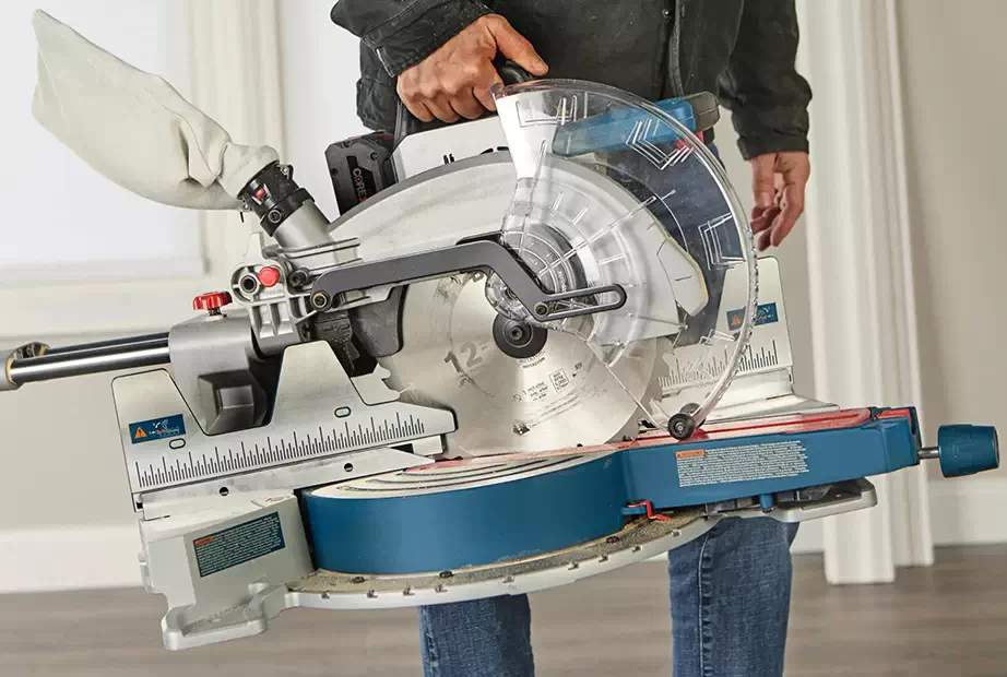 A man is handling a compact miter saw one-handedly