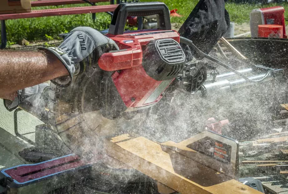 A miter saw is operating to cut a wood with lots of sawdust
