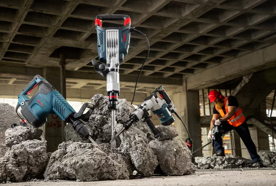 :A collection of Ronix jackhammers and a man working on a jackhammer at the background