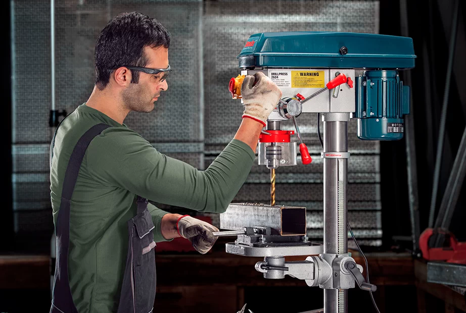 (A drill press is adjusted to drill into a metal profile