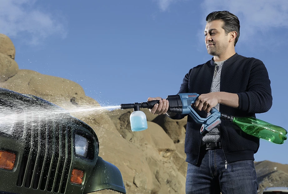  A man is washing his car with a pressure washer