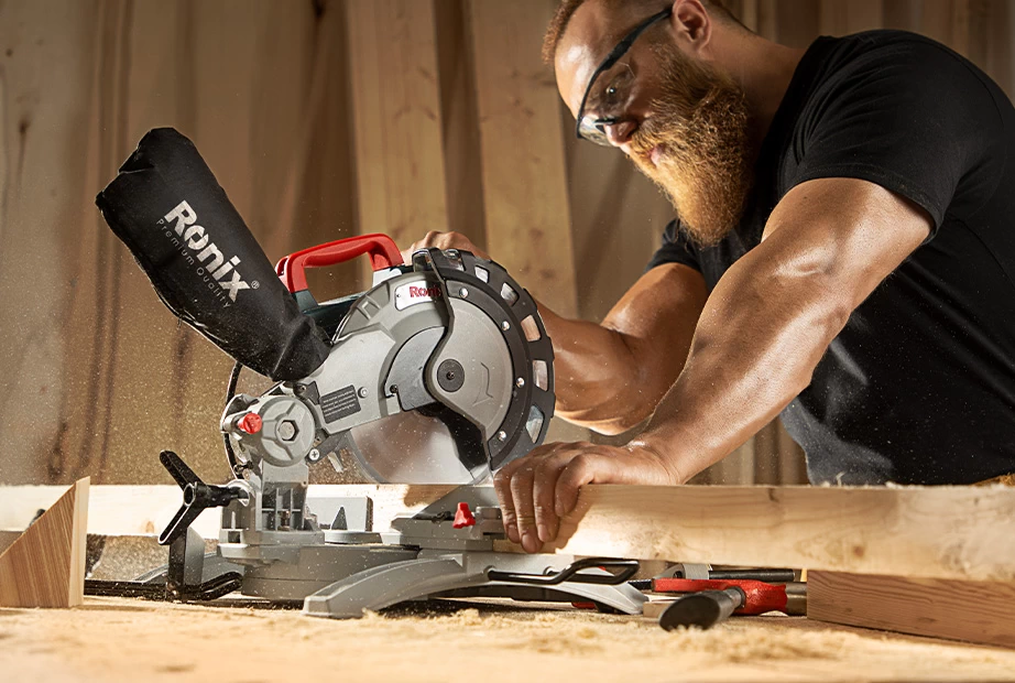A man using one of Ronix miter saws to cut through wood