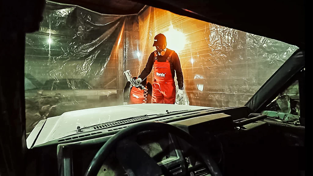 A mechanic using one of Ronix Painting guns to paint a car