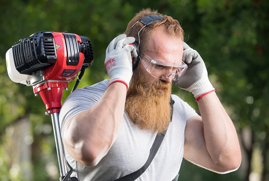 A photo of an operator wearing safety glasses, earphone and gloves to do gardening works