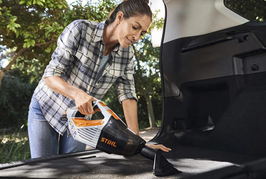 A woman is cleaning inside the car with a vacuum cleaner