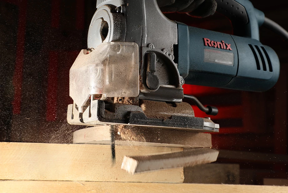 A piece of wood cut by a Ronix electric saw falls to the ground