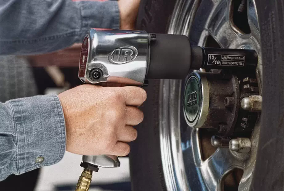 A man using a Ingersoll rand air impact wrench on a Vehicle Wheel Lug Nut