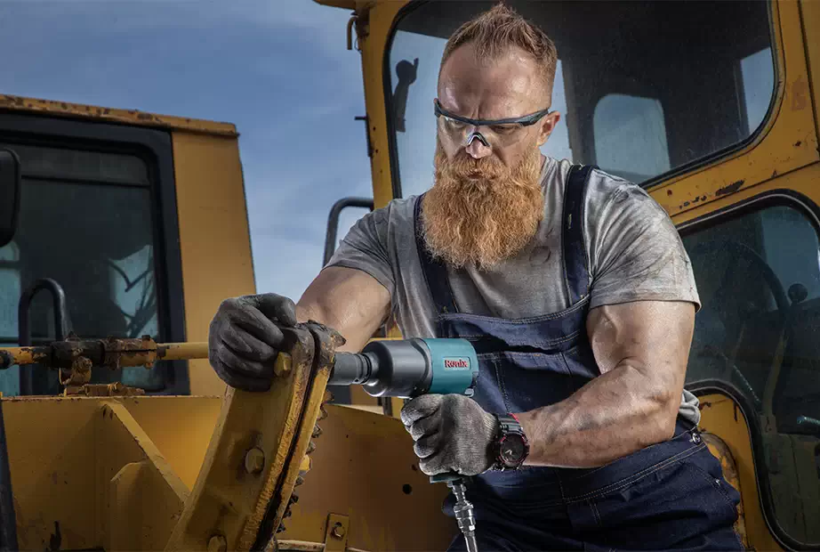 A man using one of Ronix air impact wrenches on a Loader