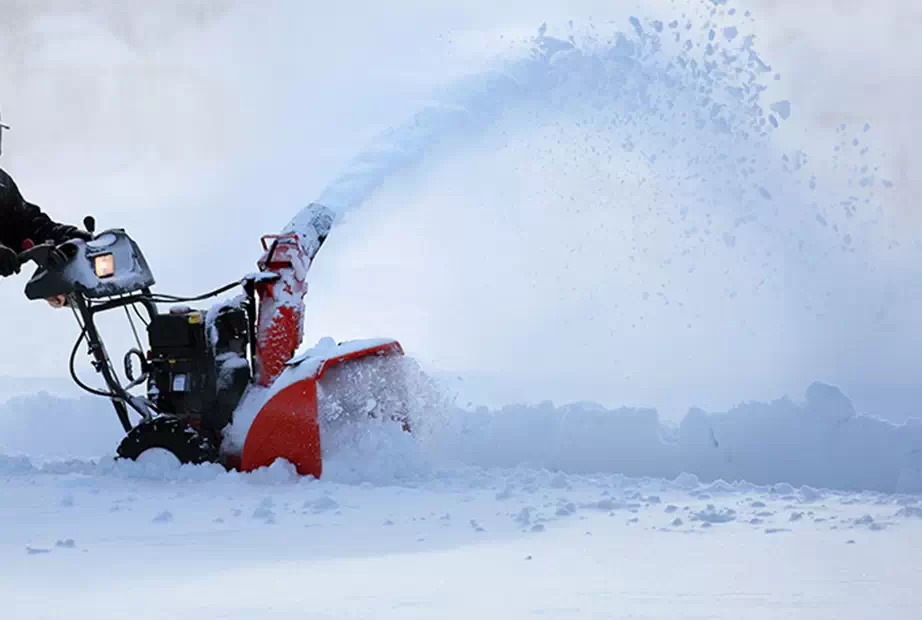 A snow blower is used to clear a driveway