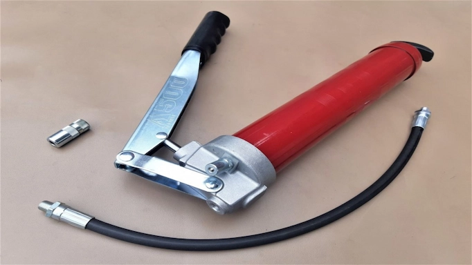 A heavy-duty manual grease gun resting on the table