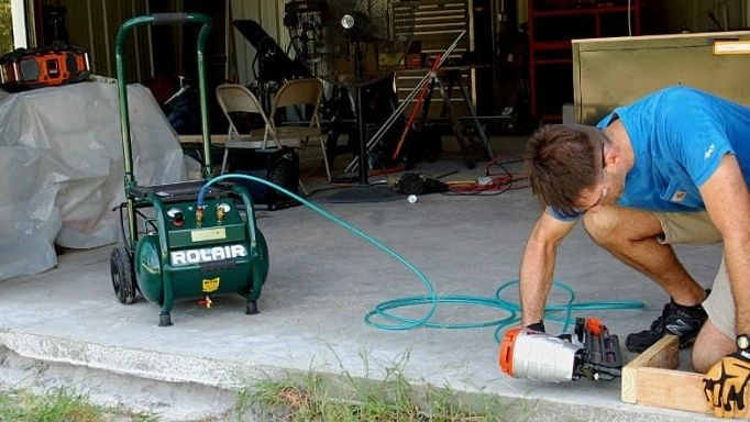 A portable air compressor being used to operate a nail gun