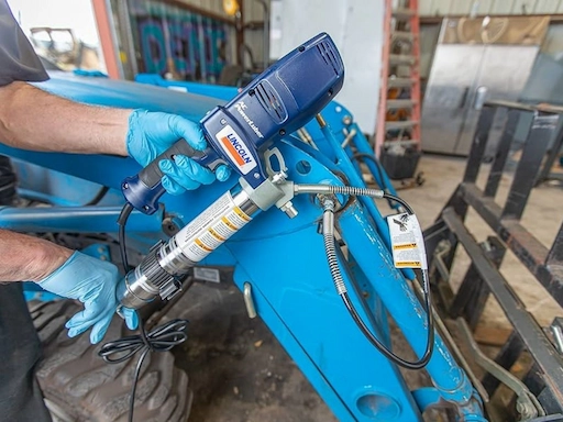 An electric grease gun is being used