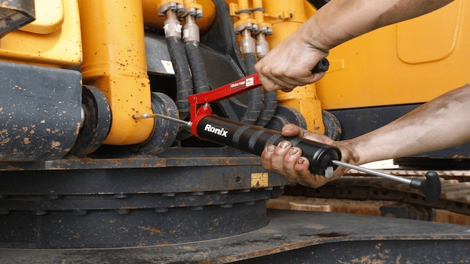 Grease gun is being used to lubricate heavy machinery parts
