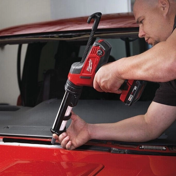 picture of a man using a gun fixing his car 
