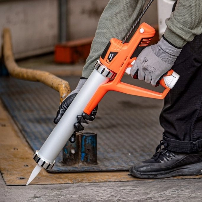 picture of a person holding an orange caulking gun 