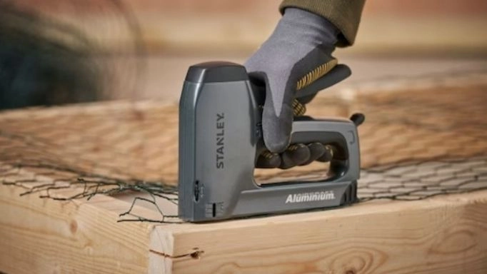 A man using a Stanley staple gun on wood