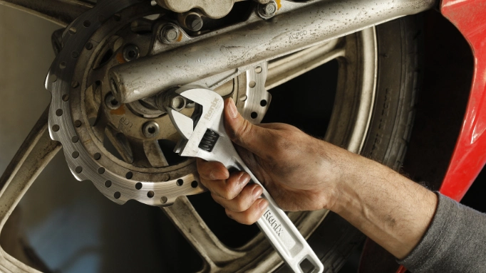 a man is tightening a bolt with adjustable wrench