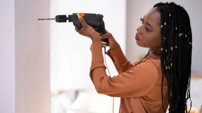 Alt: an African woman using a power drill