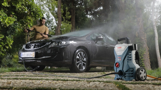 A car is being washed by a pressure washer