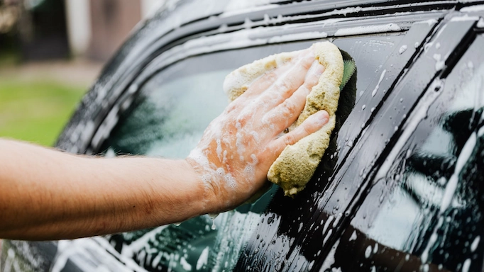 A car is being washed at home by a towel