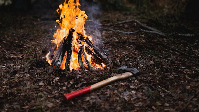 An axe is placed next to a campfire