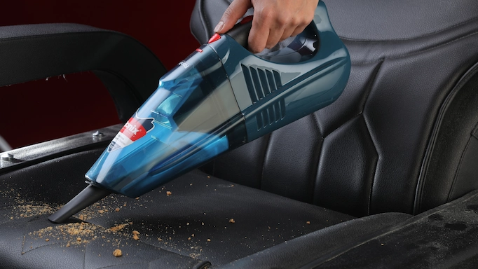 A vacuum cleaner is used to clean car seats