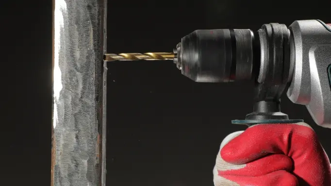 A man is about to drill through steel using one of the best drill bits for metal