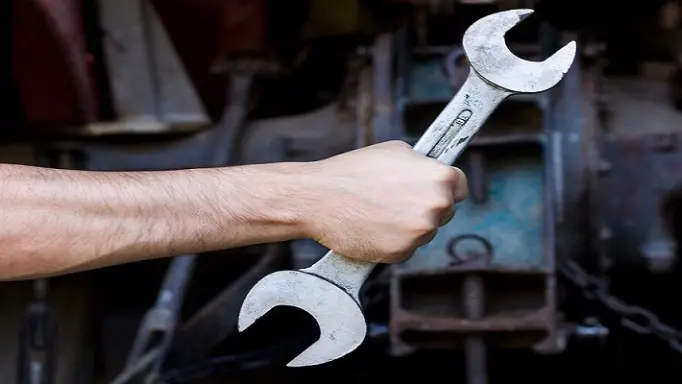 A man holding a non-ergonomic wrench