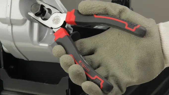 A mechanic using Ronix pliers on a car
