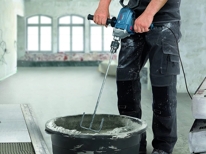 A man using a paddle mixer to blend drywall mud